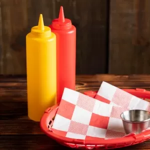 Condiment holders bottle on a table next to a ramekin